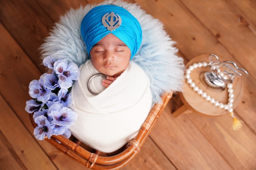 Newborn baby wearing a blue turban and swaddled.
