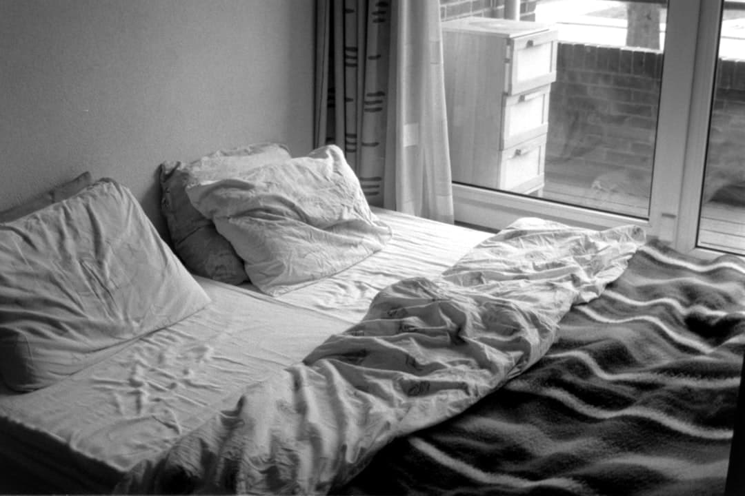 A bed is unmade near a window.