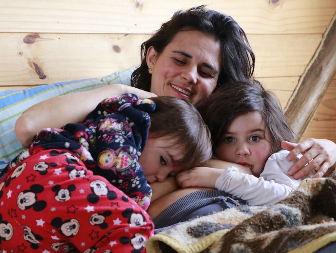 woman in white shirt lying on bed beside girl in red and white santa claus print