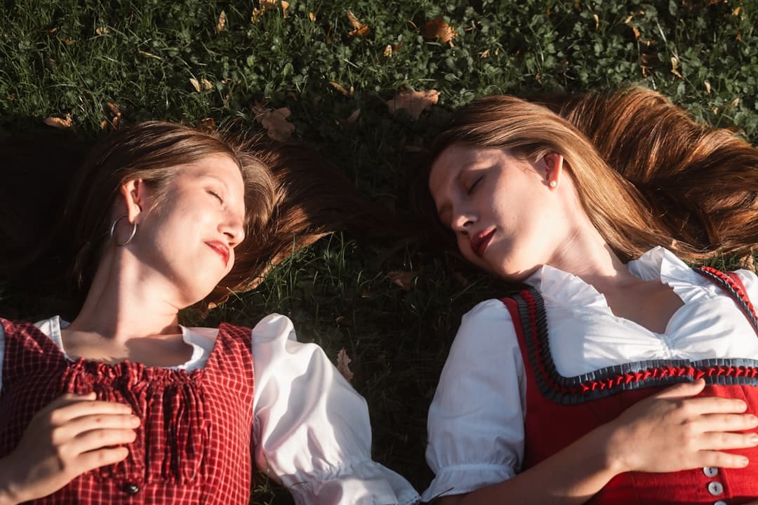 Two young women in traditional bavarian dress lying on grass.