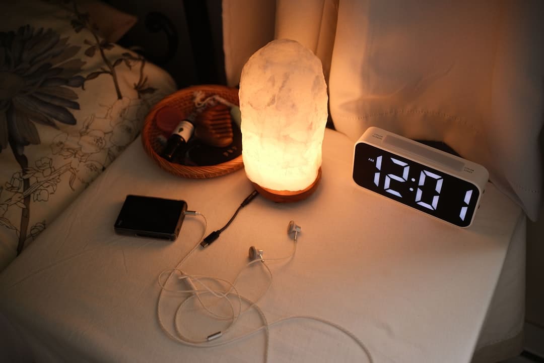 Nightstand with a lamp, clock, and chargers.